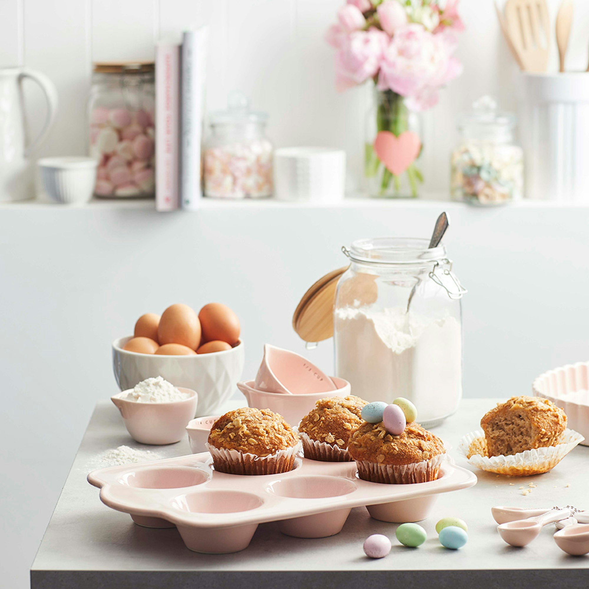 muffins in pink muffin tray with cooking ingredients and mini easter eggs